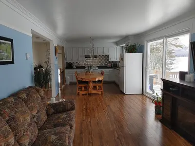 a living room with a couch and a table and a kitchen at La Parade du Huard - Lac et Spa in Saint Sebastien