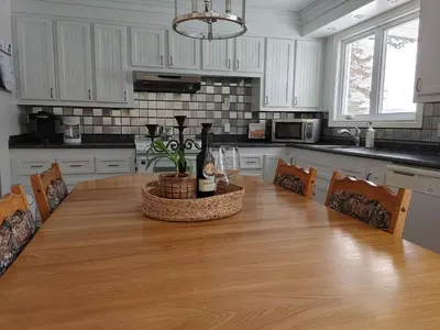 a kitchen with a wooden table with a bottle of wine at La Parade du Huard - Lac et Spa in Saint Sebastien