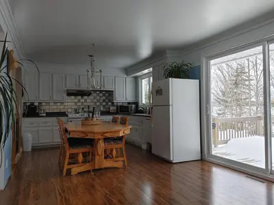 a kitchen with a wooden table and a refrigerator at La Parade du Huard - Lac et Spa in Saint Sebastien