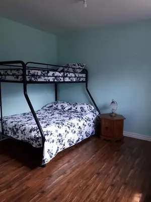 a bedroom with a bunk bed and a wooden floor at La Parade du Huard - Lac et Spa in Saint Sebastien
