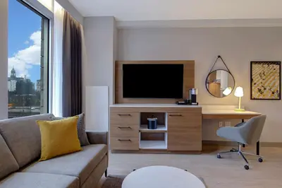 a living room with a couch and a desk with a television at Hampton Inn Montreal Downtown, Qc in Montréal