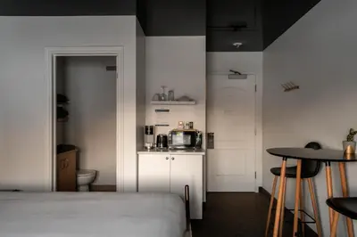 a room with a bed and a kitchen with a microwave at Au Sommet du Lac Magog in Magog-Orford