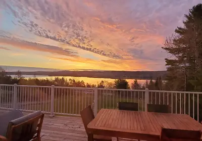 a wooden table on a deck with a sunset at Au Sommet du Lac Magog in Magog-Orford