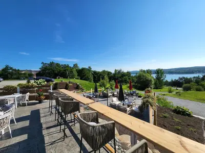 a patio with tables and chairs and a view of the water at Au Sommet du Lac Magog in Magog-Orford