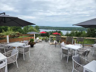 a patio with tables and chairs and umbrellas at Au Sommet du Lac Magog in Magog-Orford