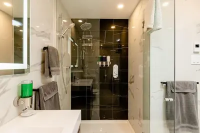 a bathroom with a shower and a sink and a glass shower stall at Plaza12 - StringLights, XL Terrace, restos & shops in Montréal