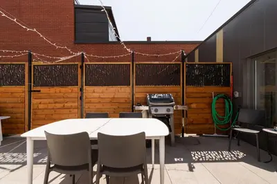 a patio with a white table and chairs and a grill at Plaza12 - StringLights, XL Terrace, restos & shops in Montréal