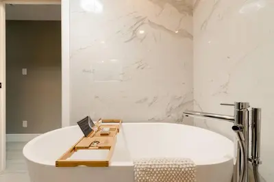 a white bath tub in a bathroom with marble walls at Plaza12 - StringLights, XL Terrace, restos & shops in Montréal