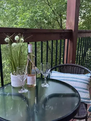 a glass table with a bottle of wine and two glasses at Condo Hôtel Magog Orford in Orford