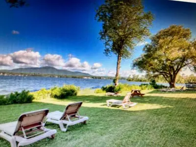 two chairs sitting on the grass near the water at Condos Memphrémagog in Magog-Orford