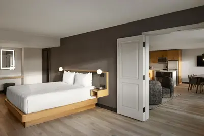 a bedroom with a white bed and a kitchen at Hyatt Place Montreal - Downtown in Montréal