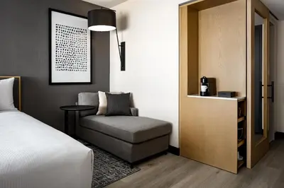 a bedroom with a bed and a chair and a table at Hyatt Place Montreal - Downtown in Montréal