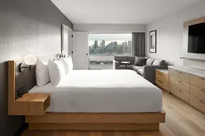 a bedroom with a large white bed and a living room at Hyatt Place Montreal - Downtown in Montréal