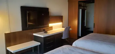 a hotel room with a desk with a tv and a bed at Grand Times Hotel Laval - Centropolis in Laval