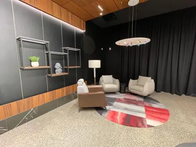 a living room with two chairs and a rug at Grand Times Hotel Laval - Centropolis in Laval