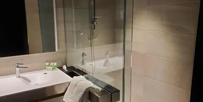 a bathroom with a glass shower and a sink at Grand Times Hotel Laval - Centropolis in Laval