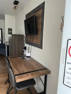 a dining room table with a tv on a wall at Motel Valois YL inc in Acton Vale
