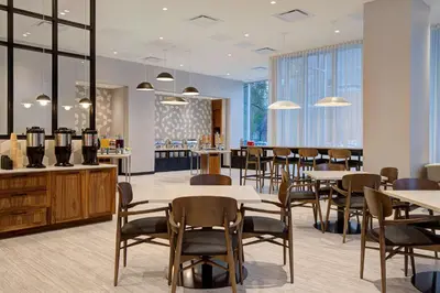 a dining room with tables and chairs and windows at Homewood Suites By Hilton Montreal Downtown in Montréal