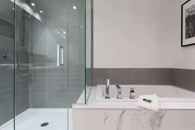 a bathroom with a tub and a glass shower at Sleek Condo in the Heart of Little Italy by Den Stays in Montréal