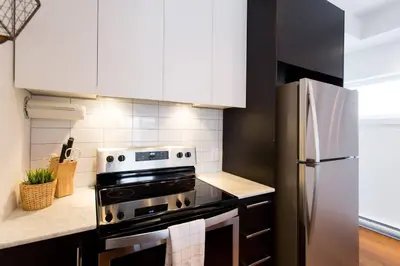 a kitchen with a stove and a refrigerator at Sleek Condo in the Heart of Little Italy by Den Stays in Montréal