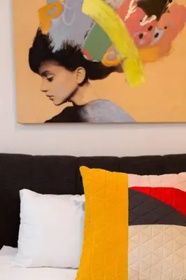 a painting on a wall above a bed with a pillow at Sleek Condo in the Heart of Little Italy by Den Stays in Montréal