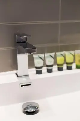 a sink with a faucet and a row of cups at Sleek Condo in the Heart of Little Italy by Den Stays in Montréal