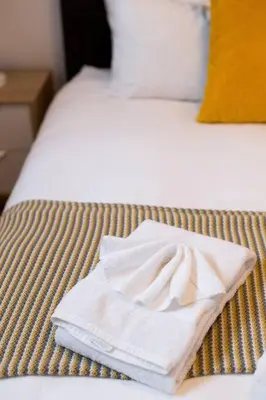 a pair of white towels sitting on a bed at Sleek Condo in the Heart of Little Italy by Den Stays in Montréal