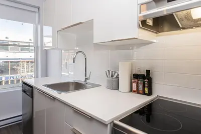 a white kitchen with a sink and a window at New, Fresh and Luminous Studio in Le Plateau by Den Stays in Montréal