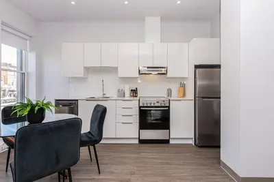 a kitchen with white appliances and a table and chairs at New, Fresh and Luminous Studio in Le Plateau by Den Stays in Montréal