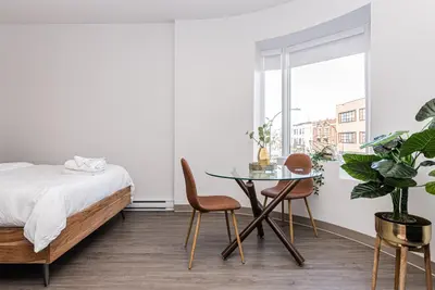 a bedroom with a bed and a table and chairs at Huge New Flat well Located closed on St-Denis Street by Den Stays in Montréal