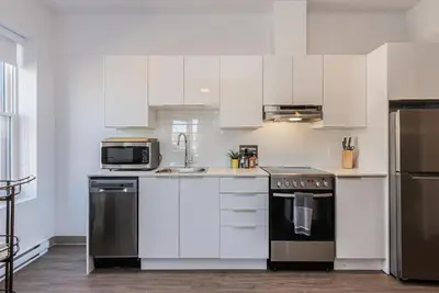 a kitchen with white cabinets and stainless steel appliances at Huge New Flat well Located closed on St-Denis Street by Den Stays in Montréal