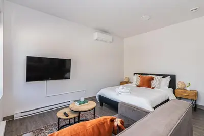 a bedroom with a bed and a dog sitting on a couch at Wonderful New Studio close to Mount Royal By Den Stays in Montréal
