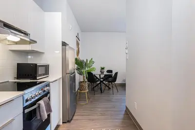 a kitchen with white appliances and a table with chairs at Wonderful New Studio close to Mount Royal By Den Stays in Montréal