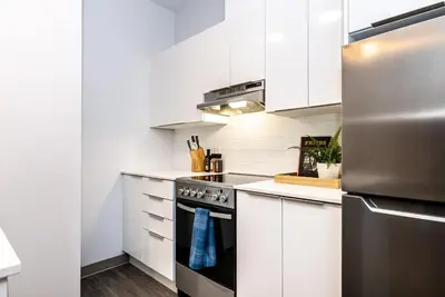 a kitchen with white cabinets and a stainless steel refrigerator at New Urban and Well Located 1 Bedroom Apartment by Den Stays in Montréal