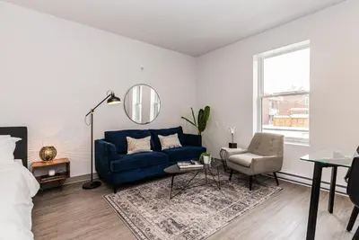 a living room with a blue couch and a chair at Modern and New Studio in the Heart of the City by Den Stays in Montréal
