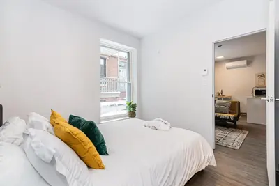 a white bedroom with a bed with yellow pillows at New and Perfectly Located 1 Bedroom Apartment by Den Stays in Montréal
