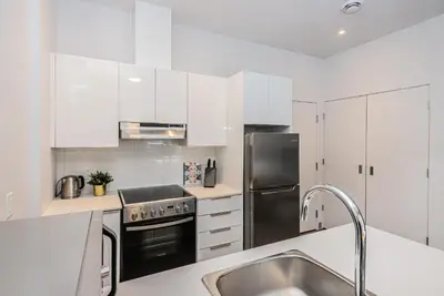 a kitchen with white cabinets and a stainless steel refrigerator at New and Perfectly Located 1 Bedroom Apartment by Den Stays in Montréal
