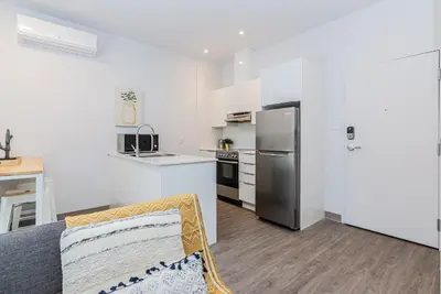 a kitchen with a couch and a refrigerator in a room at New and Perfectly Located 1 Bedroom Apartment by Den Stays in Montréal