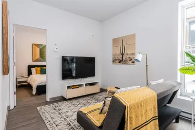 a white living room with a tv and a couch at New and Perfectly Located 1 Bedroom Apartment by Den Stays in Montréal