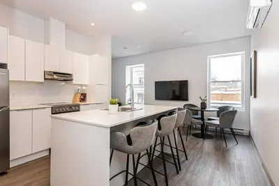 a kitchen with white cabinets and a bar with stools at Stylish & Fun 1 Bedroom Apartment in Le Plateau by Den Stays in Montréal