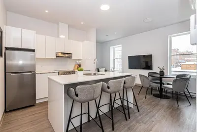 a kitchen with white cabinets and a bar with stools at Stylish & Fun 1 Bedroom Apartment in Le Plateau by Den Stays in Montréal