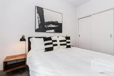a bedroom with a white bed with a black and white pillow at Stylish & Fun 1 Bedroom Apartment in Le Plateau by Den Stays in Montréal