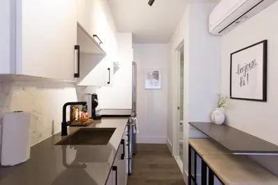 a kitchen with white cabinets and black countertops at Perfect Business Trip Studio with Full Amenities by Den Stays in Montréal