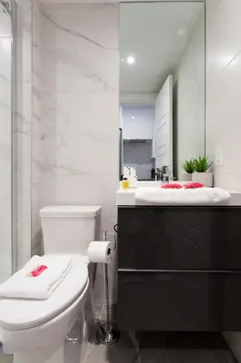 a bathroom with a white toilet and a mirror at Blue Tropics Studio in Little Italy with kitchen by Den Stays in Montréal
