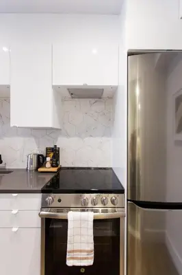 a kitchen with a stove and a stainless steel refrigerator at Blue Tropics Studio in Little Italy with kitchen by Den Stays in Montréal