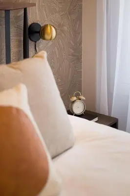 a bed with a pillow and a clock on a table at The Santamaria Golden Palms Studio by Den Stays in Montréal