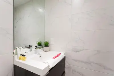 a white bathroom with a sink and a mirror at The Santamaria Golden Palms Studio by Den Stays in Montréal