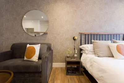 a bedroom with a bed and a chair and a mirror at Scandinavian Studio with Full Kitchen and Bath by Den Stays in Montréal