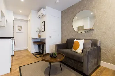 a living room with a couch and a mirror at Scandinavian Studio with Full Kitchen and Bath by Den Stays in Montréal