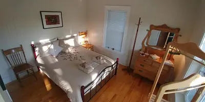 a bedroom with a bed with a mirror and a dresser at Au Coeur des Jardins in Compton